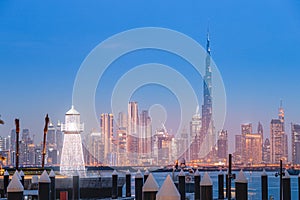 decorative lighthouse at the background of famous Burj Khalifa skyscraper tower in the Dubai Creek Marina Harbor.