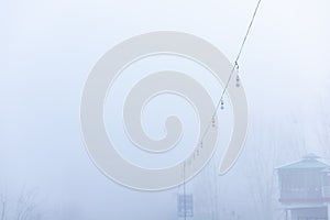 Decorative lights hanging outside on a wire in fog