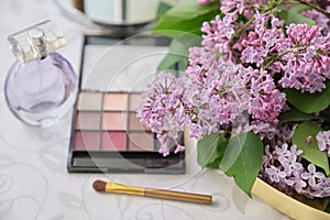 Decorative makeup cosmetics, bottle of perfume, eye shadow, fresh lilac flowers