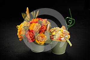 Decorative metal buckets filled with orange flowers and sweet candies of various shapes