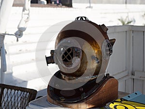 Decorative metal diving helmet on a rack against a background of white wooden walls