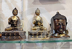 Decorative metal figurines of Buddha in a meditative pose on shop window