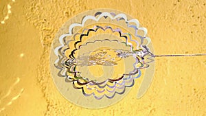 Decorative metal pendant, rotating, glitter and reflections with the sunlight.