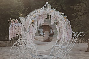 Decorative metal wedding carriage with flowers and a blurred background