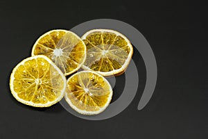 Decorative orange slices lie on a black matte surface. Still life on a black table