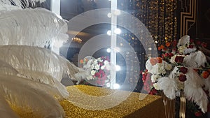 Decorative ostrich feathers on a gold table next to a make-up mirror