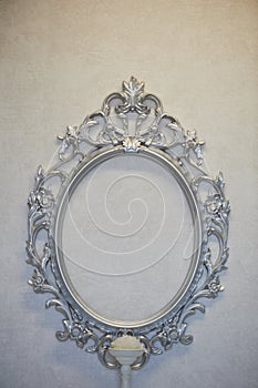 Decorative oval frame hanging on the gray wall. Classic decor, framing