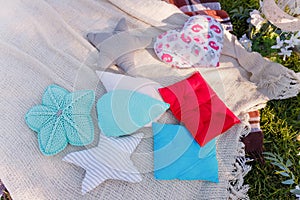 Decorative pillow on plaid for outdoors picnic. Stars, heart, waterdrops and flower shaped colorful cushions. Leisure, birthday