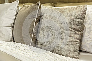 Decorative pillows on the bed. Grey-beige fabric. Comfort, style and beauty in the interior of the house. Close-up