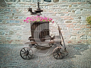 Decorative Pink Flowers in a Big Wooden Vase with an Antique Metallic Instrument inside an Old Wooden Trolley with Wheels