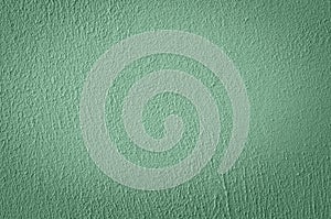 Decorative plaster on the wall, painted green. Close-up, abstract textured background