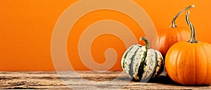 Decorative pumpkins on wooden table on orange background. Harvest, Thanksgiving Day banner design