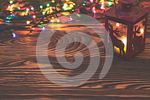 Decorative red metal lantern with a deer cutout lit by a glowing candle with christmas light and copyspace for Christmas