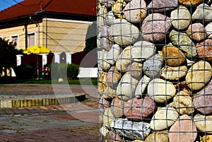 Decorative riverstone closeup in wire mesh. soft background with house exterior