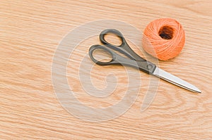 decorative rustic orange yarn ball and scissors on a wooden tabletop