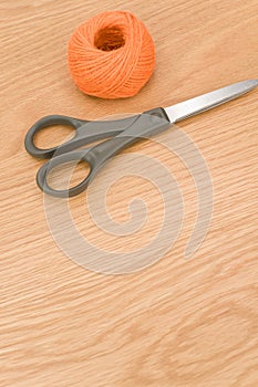 decorative rustic orange yarn ball and scissors on a wooden tabletop