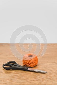 decorative rustic orange yarn ball and scissors on a wooden tabletop