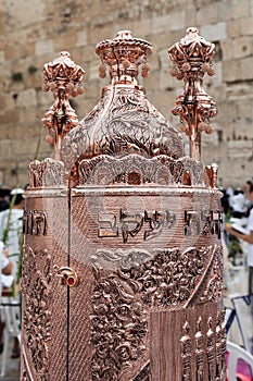 A decorative, Sephardic style Torah in a copper case designed with Jewish symbols.