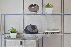 Decorative shelf on wall with books, black caps, wooden clock