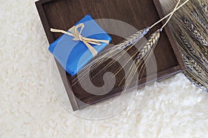 Decorative soap gift on a wooden box and dry blue rye spikes