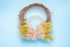 Decorative spring wreath with bright yellow flowers on pastel light blue background