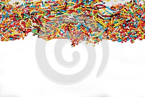 Decorative sprinkles border on white background. Multicolor Sugar confectionery powder in the corner. Scattered sweet sugar sticks