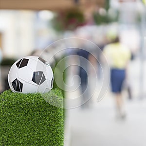 Decorative stand in the form of the classic football ball in the net on the green grass. Ornaments of city streets