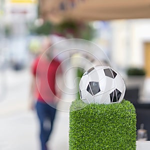 Decorative stand in the form of the classic football ball in the net on the green grass. Ornaments of city streets