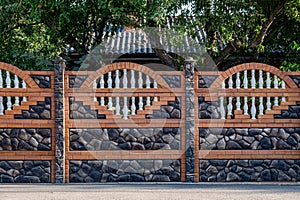 Brown decorative stone fence with baluster. against the house
