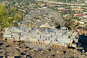 Decorative stone resting place or bench on the top of moutain trail overlooking the suburban parts of Tuscon Arizona