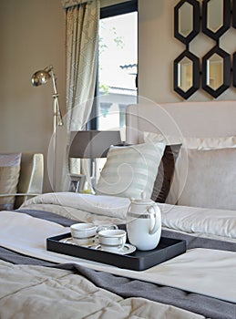 Decorative tea cup set on black tray in modern bedroom interior