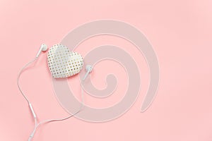 Decorative textile volume heart and white headphones on pink background. Concept Listen to your heart. Top view Copy space Flat