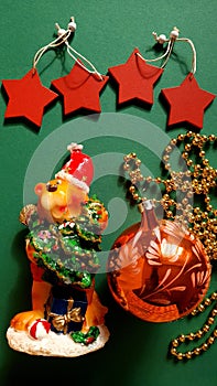 Decorative tiger candle, Christmas tree orange ball, golden garland, red stars on a green background.