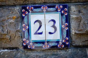Decorative tile with the number 23, set on a stone wall