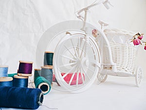 decorative toy bike, dried rosebuds and thread on white background