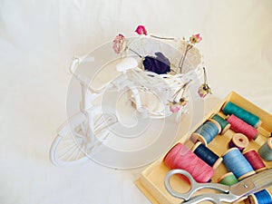 decorative toy bike, dried rosebuds and thread on white background