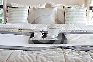 Decorative tray with black tray of tea set on the bed in modern bedroom interior