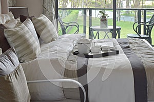 Decorative tray with book and tea set on the bed in modern bedroom