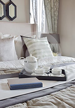 Decorative tray with book and tea set on bed in modern bedroom