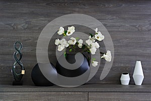 Decorative vases and flowers at dark wooden shelf