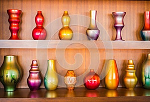 Decorative vases on wooden shelf .