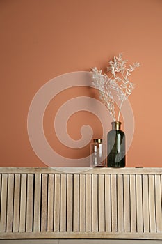 Decorative vases on wooden shelf near wall indoors