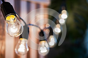 Decorative vintage edison light bulbs against striped wooden wall background.