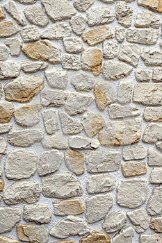 Decorative wall made of natural stones of different sizes, colors and shapes plastered with white mortar as a background photo