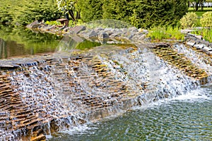 Decorative waterfall in the summer garden. Running water along a dripping slope. Landscape design