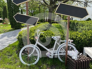 A bicycle with a flower basket at the entrance to the park. Decorative white bicycle for decoration in the garden. Decor with