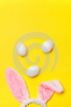 Decorative white eggs and bunny ears furry costume toy isolated on trendy yellow background