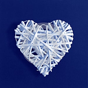 Decorative white heart on grey canvas texture background made of Classic Blue 2020 color. Color of year 2020 blurred sparkling