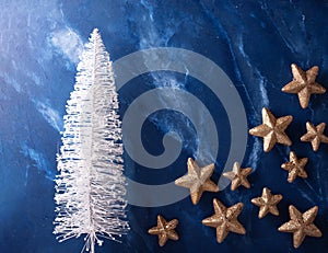 Decorative white holiday tree and golden stars against depp blue textured wall. photo