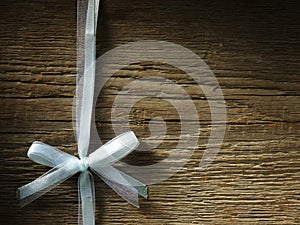 Decorative white ribbon and bow over wooden background